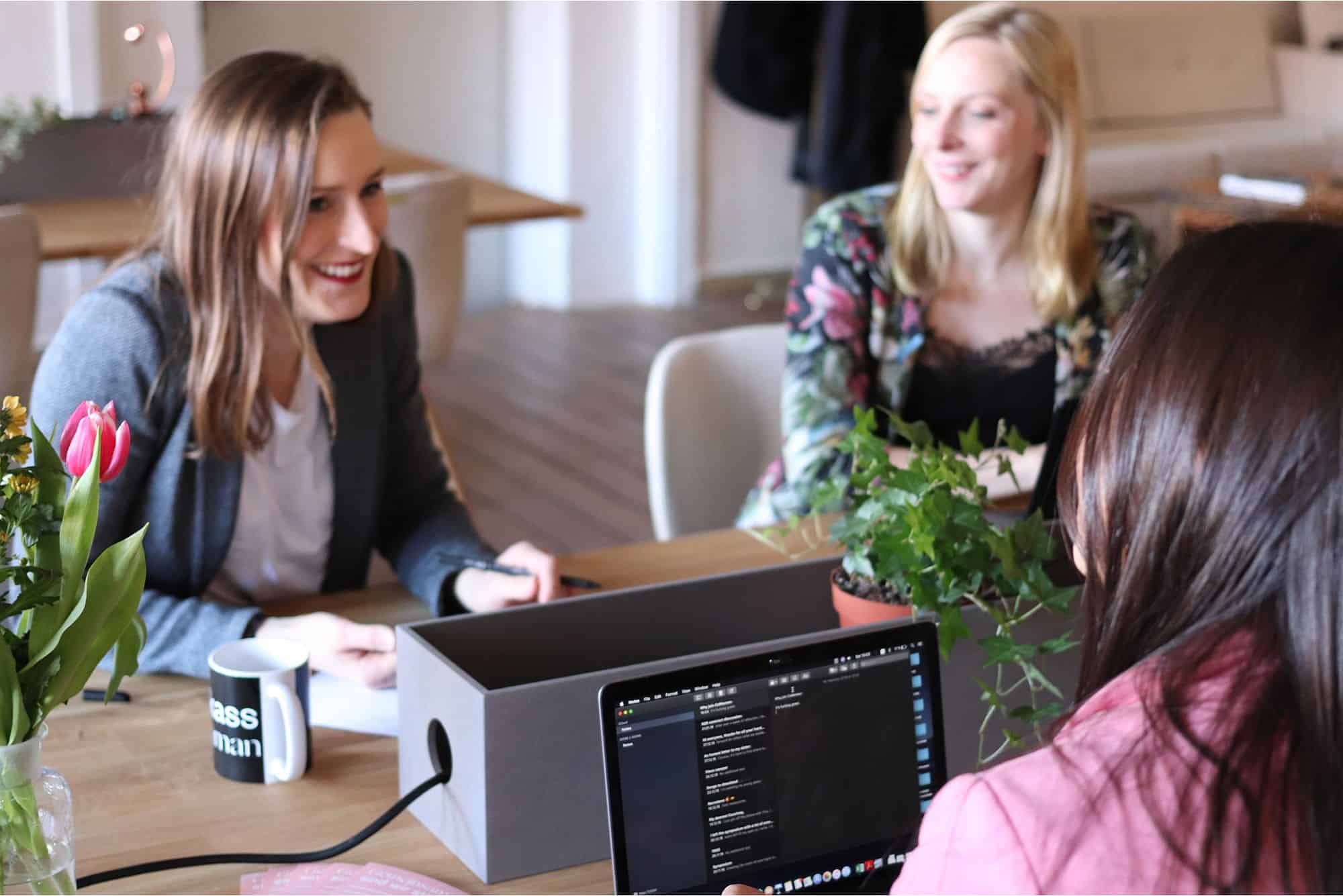 Three women technology professionals sitting at long table discussing artificial intelligence staffing and talent solutions